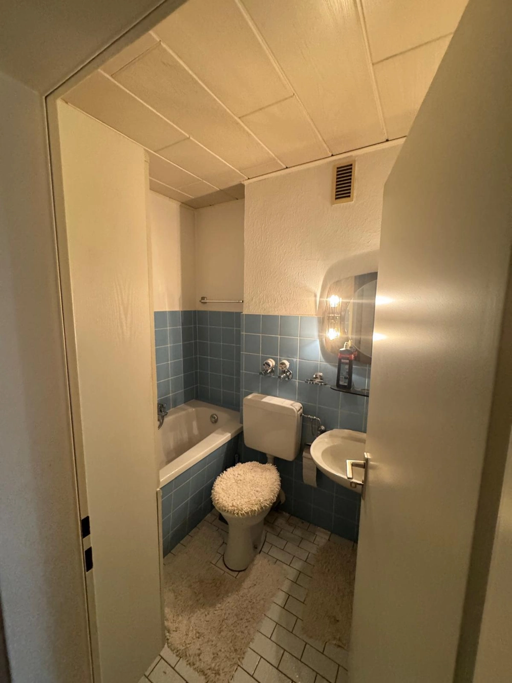 Kleines Badezimmer mit blauen Fliesen, Badewanne, WC und Waschbecken – Badsanierung