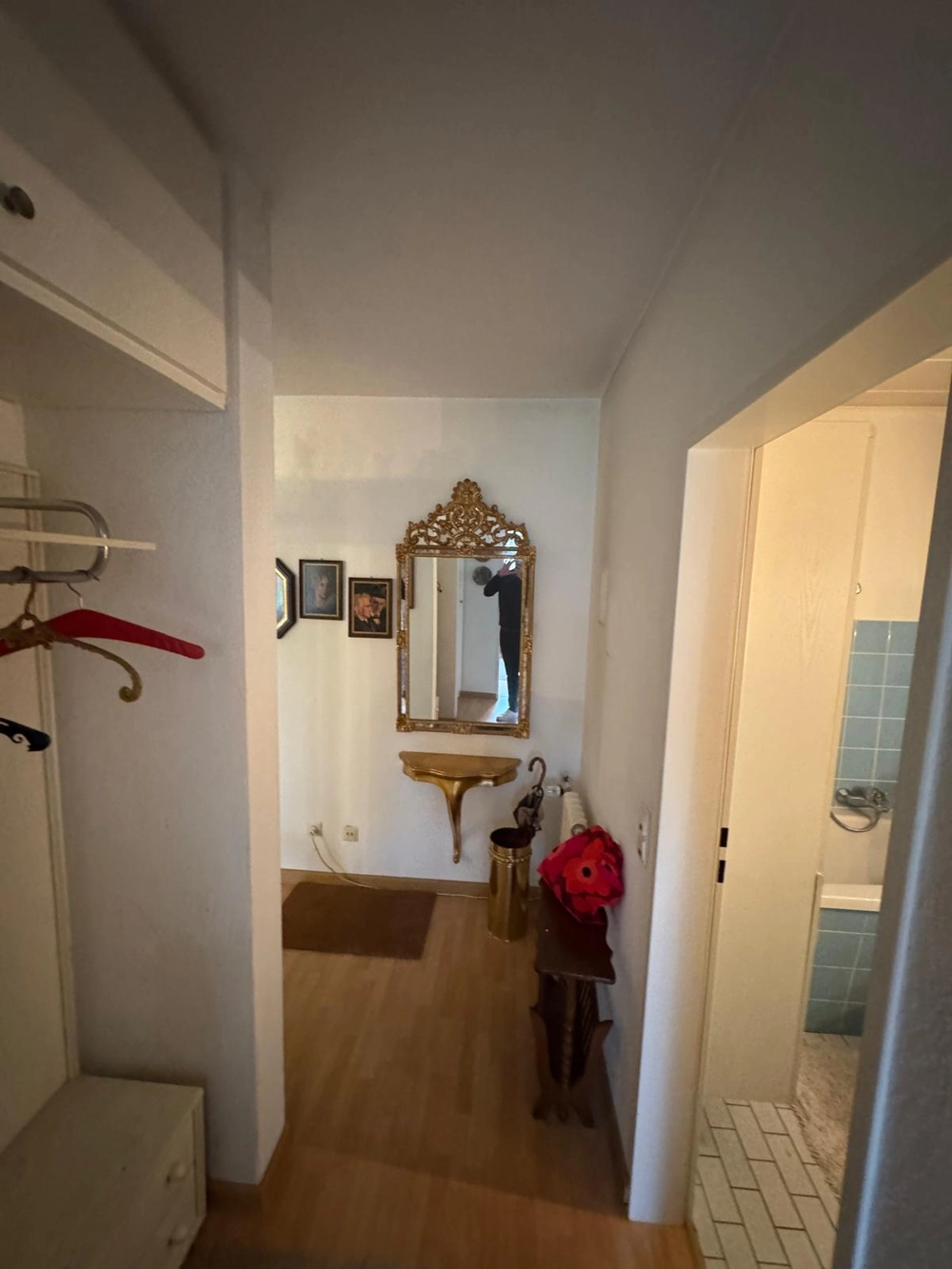 Laminat verlegen: Flur mit neu verlegtem Laminatboden, goldverziertem Wandspiegel und Ablagekonsole