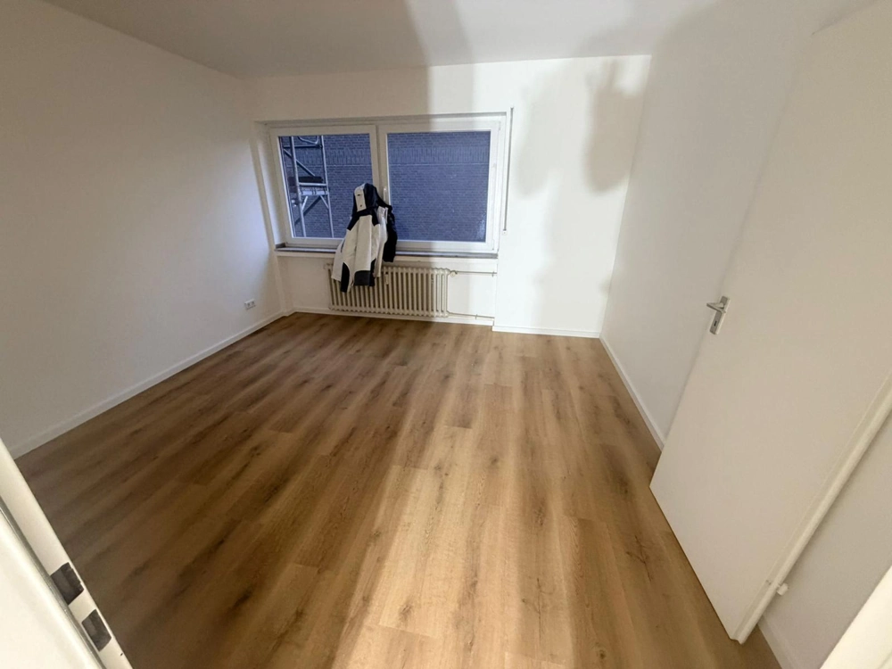 Leeres Zimmer mit frisch verlegtem Laminatboden und weißen Wänden, Laminat verlegen