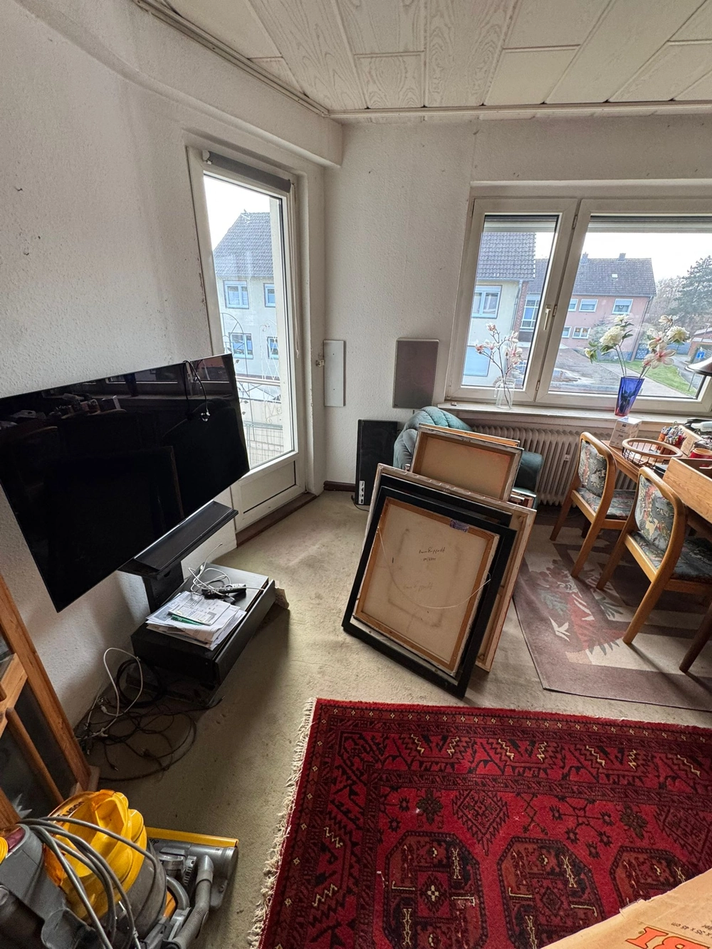 Entrümpelung im Wohnzimmer mit gestapelten Bilderrahmen, Fernseher und Möbeln