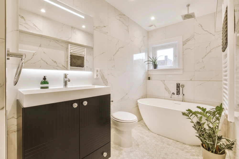 Badsanierung: Modernes Badezimmer mit freistehender Badewanne, Waschtisch, Toilette und Pflanzen