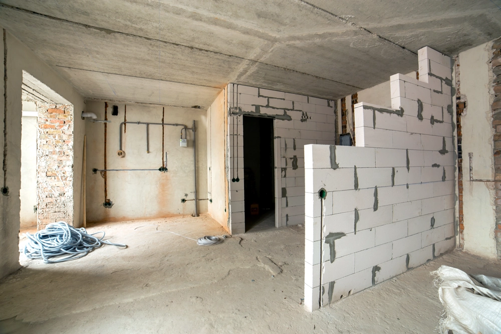 Halbfertige Porenbeton-Trennwand und sichtbare Elektroleitungen in Rohbau eines Wohnraums – Trockenbau
