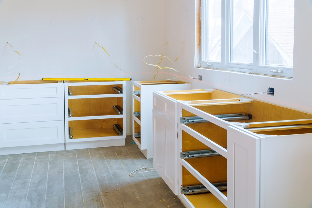 Unfertige weiße Küchenunterschränke mit Schubladenauszügen vor der Endmontage im Rahmen der Küchenrenovierung