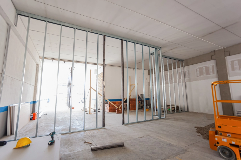 Innenraum im Rohbau mit Metallständerprofilen, Helm und Werkzeugen für Trennwände bauen