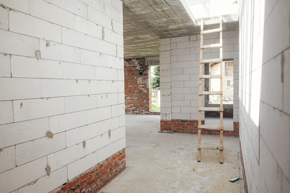 Rohbau-Innenraum mit Trockenbau-Trennwänden aus Porenbeton und Holzleiter